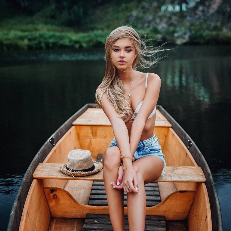 Очень красивая обнаженная блондинка с корзинкой яблок на берегу реки