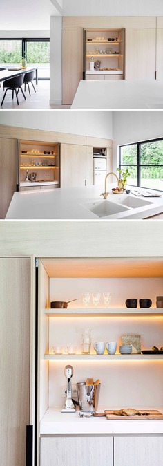 In this modern kitchen, minimalist black cabinet hardware allows you to easily open the cabinet, with the doors folding away within the cabinetry. One design feature hidden within this particular cabinet with an internal countertop, is the LED lighting that's hidden behind the shelves to brightens up the space without having to turn on the main kitchen lights.