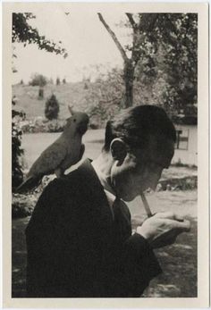 Marcel Duchamp lighting a cigarette with a bird on his shoulder #photography #people