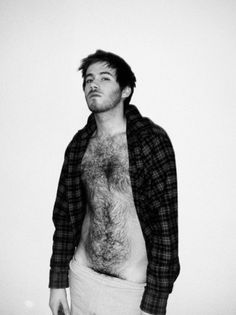 A black-and-white portrait of a young man with a hairy chest, showcasing his youthful charm.