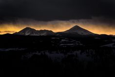 Silhouettes of snow-covered mountains against the orange sunset sky in Silverthorne
