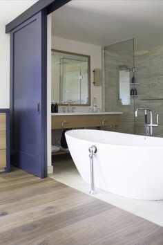 The designers used a neutral palette with durable, sealed stone in the bathrooms. Most rooms have large soaking tubs; here, the large ensuite bath can be hidden from the room via blue-painted sliding doors.