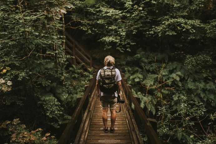 A man with a backpack and a camera on a boardwalk in a forest