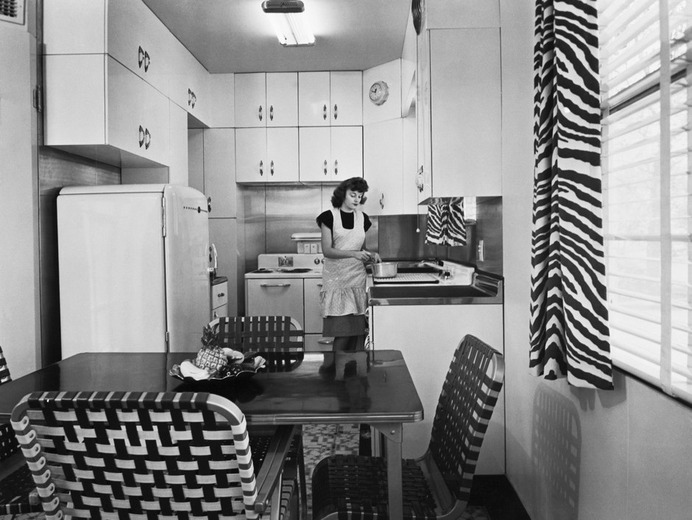 A woman cooks in a small 1940s-era kitchen. Bettmann/Getty Images