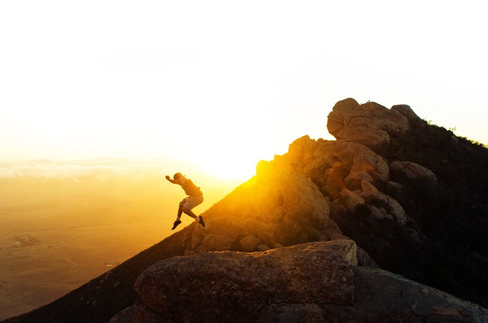 man jumping on the cliff during golden hour