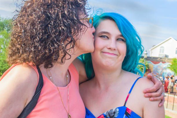 Mother hugging, kissing daughter, outdoors, smiling