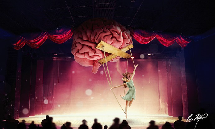 This artwork is a surrealist photo composite of a woman performing as a puppet controlled by a brain. Photos provided by Adobe stock and manipulated to create a composition.