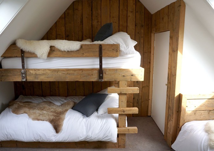 A bunk room with rustic wood and sumptuous linens.