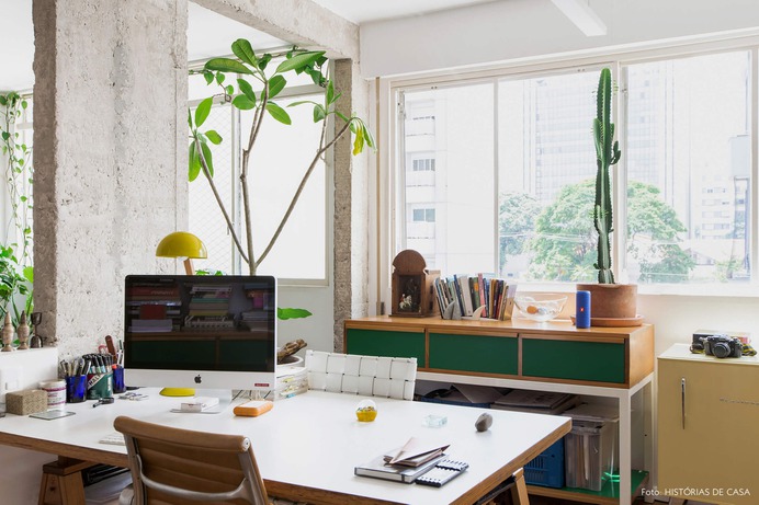 Home office com móvel de formica colorida e muitas plantas