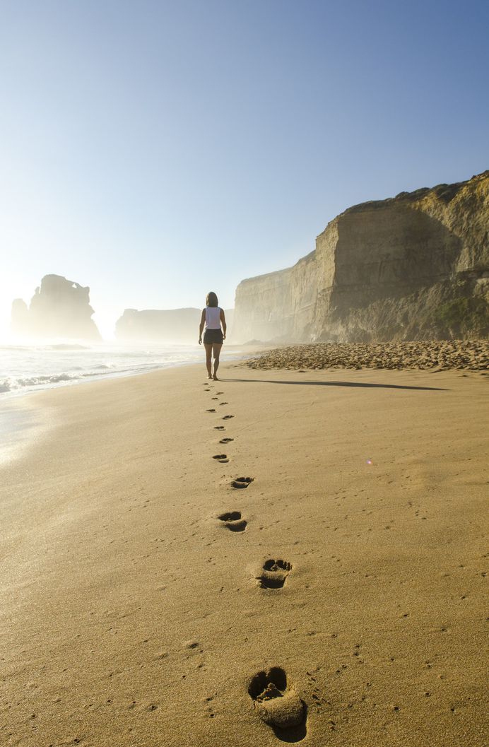 Woman leaving footprints in the sand at sunset
