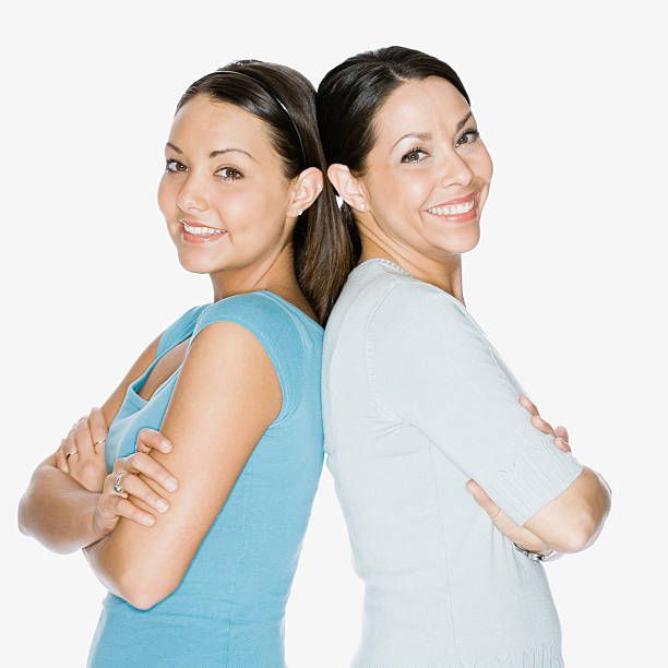Hispanic mother and daughter standing back to back