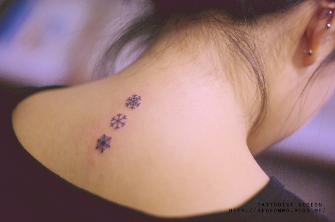 Fine line snowflakes tattooed on the wrist.