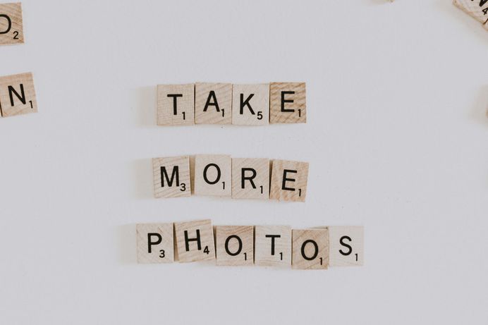 Scrabble letter pieces that spell out "Take more photos."