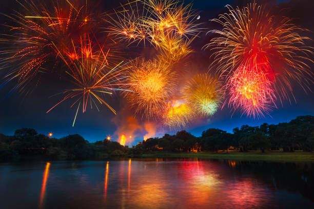 Colorful fireworks exploding above pond