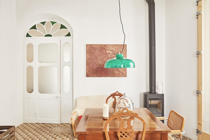 A dining area with an old farm table, high back antique chairs, and vintage Breuer Cesca Chairs. Hanging above is vintage light in green (for something similar, see our post 10 Easy Pieces: Colorful Glass Pendant Lights and the Kartell Fl/y Suspension Light).