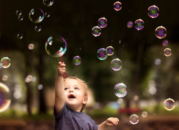 2 Year Old Fraternal Twin Boy Hold a Bubble Want and Plays with Floating Bubbles in a Park
