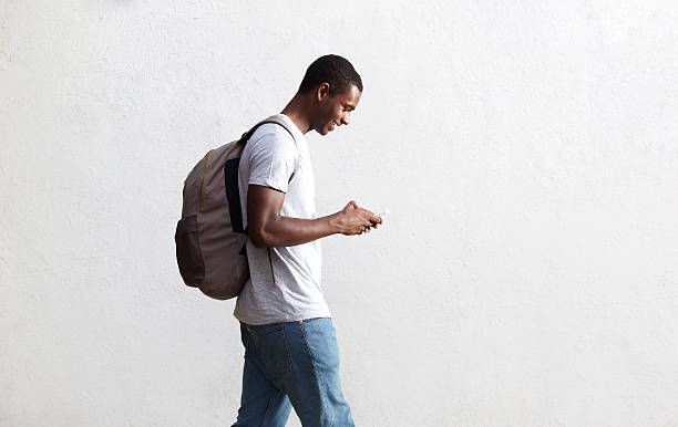African american student walking with bag and mobile phone