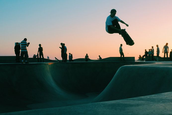 Skateboarder performing an aerial during sunset at Venice Skatepark in Los Angeles, California