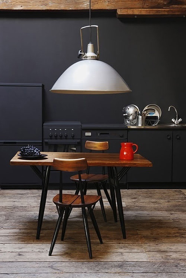Love the black cabinets and walls and how the appliances blend into it...especially against the wood table and awesome pendant light! #kitchen