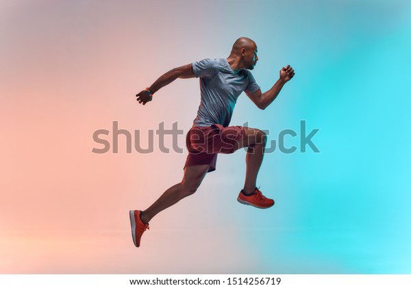 New champion. Full length of young african man in sports clothing jumping against colorful background