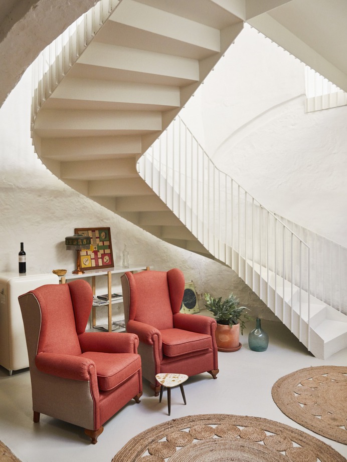 In the basement kitchen and lounge area, two vintage armchairs reupholstered by Archimoldi, a firm out of Barcelona. The mini fridge behind them is the Klarstein PopArt-Bar Minibar Fridge and circular jute rugs are the Dandelion Rugs from Armadillo & Co.