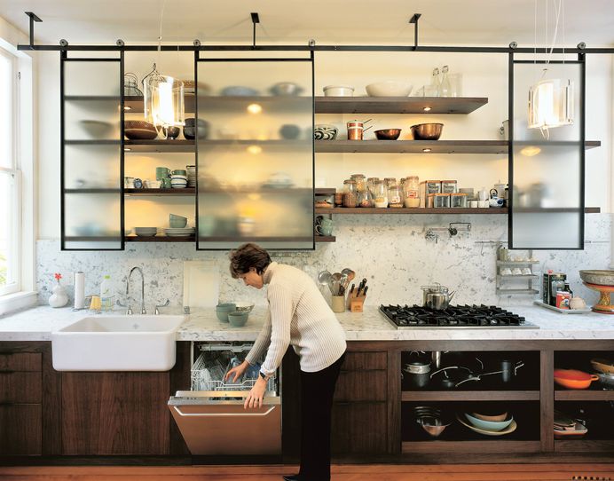Kitchen, Cooktops, Recessed Lighting, Open Cabinet, Marble Counter, Medium Hardwood Floor, Vessel Sink, Marble Backsplashe, Pendant Lighting, and Wood Cabinet The Felds’ new kitchen is clean, modern, and laced with industrial touches (laboratory faucets, lab glass pendant lamps designed by Sand, stainless steel appliances) while animated by materials and crafted elements that radiate warmth: fir floors unearthed from beneath two layers of linoleum; a fireclay farm sink made in England; Carrera marble counters that extend up the walls; walnut shelving; and industrial mechanisms that put the hardware on display, such as the suspended rolling blackboard that conceals the water heater. Photo 74 of 2509 in Best Kitchen Photos from Victorian Revival