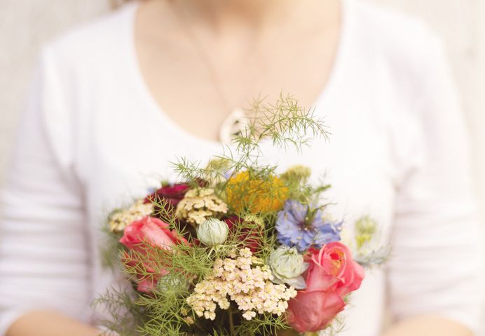 A woman holding a modest bouquet with various flowers