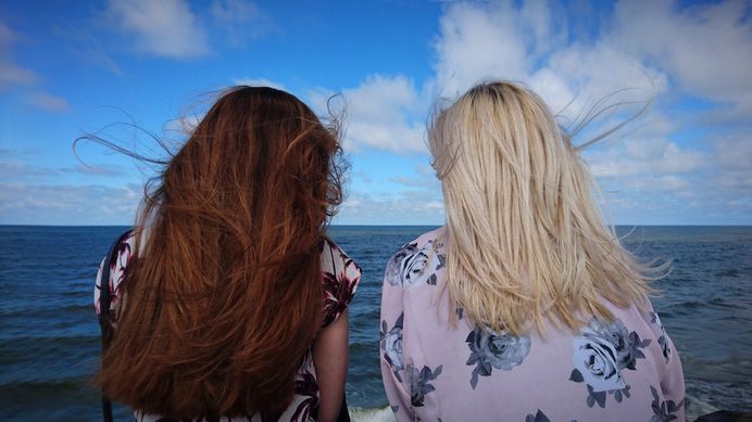 Two friends sitting and talking on the ocean shore