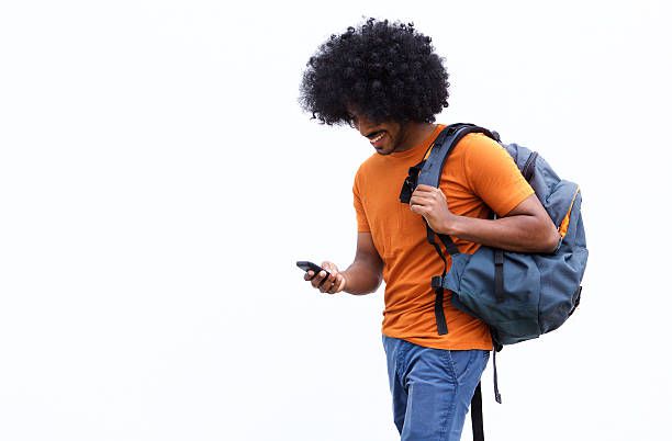 Smiling young man walking with bag and mobile phone