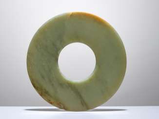 A SMOOTHLY POLISHED BI DISC WITH SHINY SURFACES CARVED FROM GREEN JADE WITH BROWN STRIPES