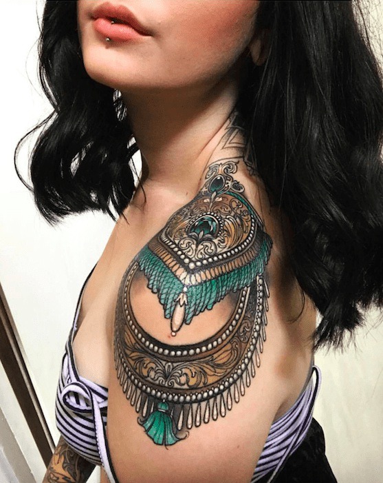 Girl with shoulder tattoo of tapestry style beads and tassels