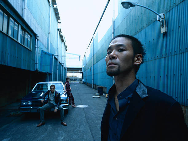 Man standing, a couple beside a car in background