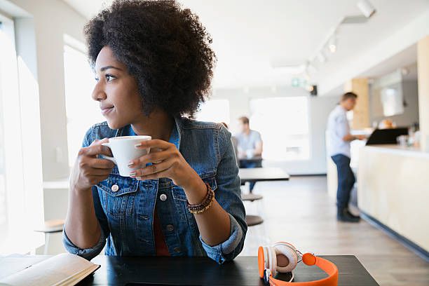Pensive woman drinking coffee looking away in cafe