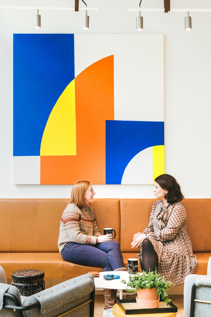 two women on tan couch with painting, 4 by 3