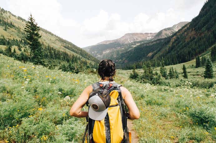 A woman with a large backpack on a trail in the mountains