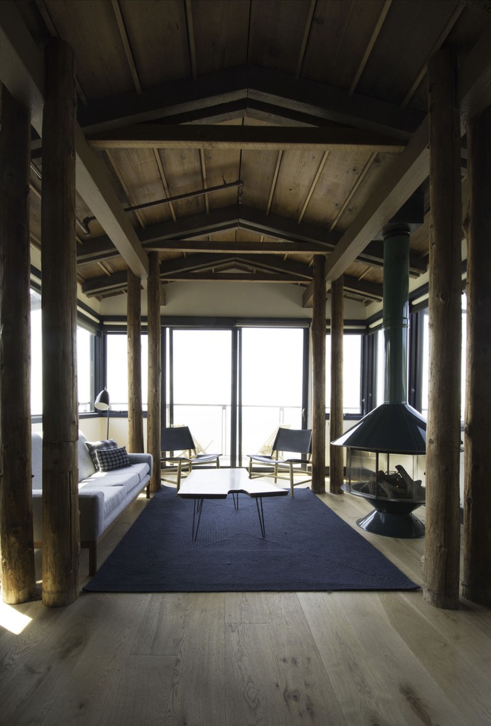 The dramatic living room of an ocean view suite retains the structure's original log framing with expanded windows to let in more light and views. Every hotel room has a Rais or Wittus gas fireplace, controlled via Nest.