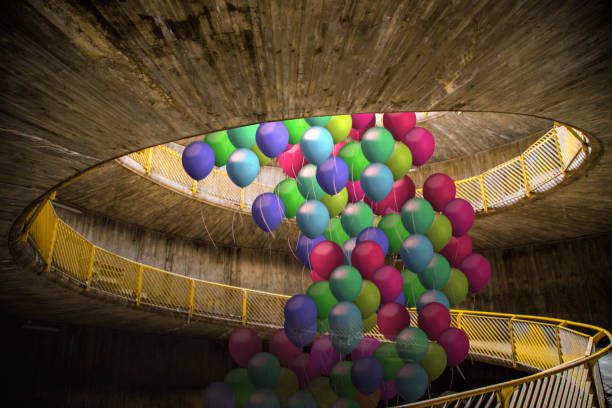 Creative picture of group of colorful helium balloons flying in the middle of cool spiral ramp in the city.