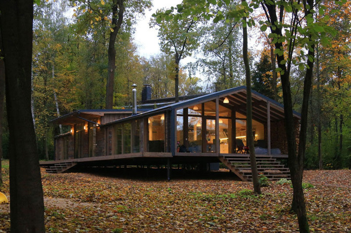 This rustic modern house in a forest has a modular design, with metal framing combined with barn board and glass to create a look that fits