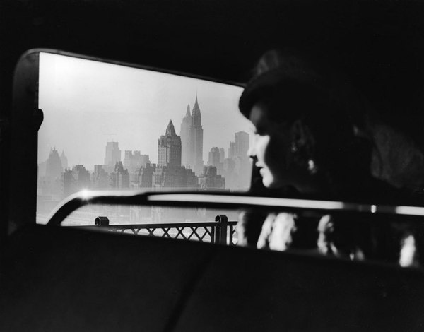 Departing from New York City as she crosses the 59th Street Bridge a shrouded woman gazes back at the iconic Midtown skyline in 1940..jpg (9 #vogue #white #woman #focus #dramatic #midtown #black #vintage #and #york #skyline #new