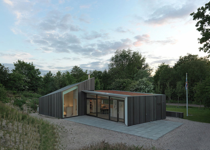 Timber holiday home huddles behind dunes on Dutch island