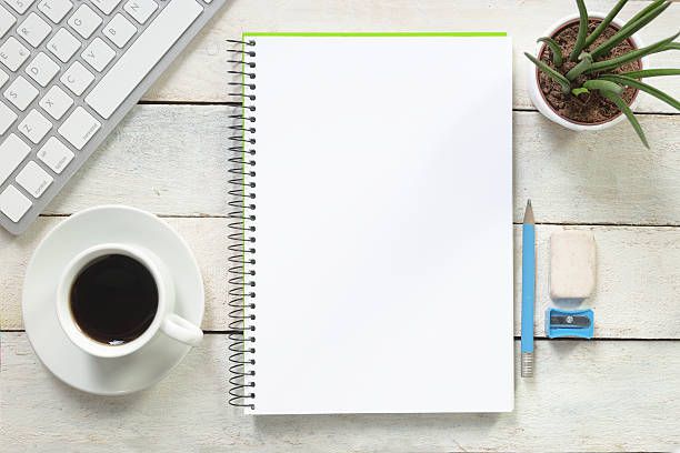 Empty notebook on a white wooden table at coffee time.