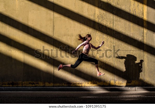 Young fit blonde woman jumping in the street
