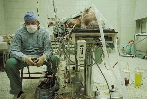 Cirurgião cardiovascular após um transplante de coração bem sucedido e que durou 23 horas. Seu assistente dorme no canto da imagem