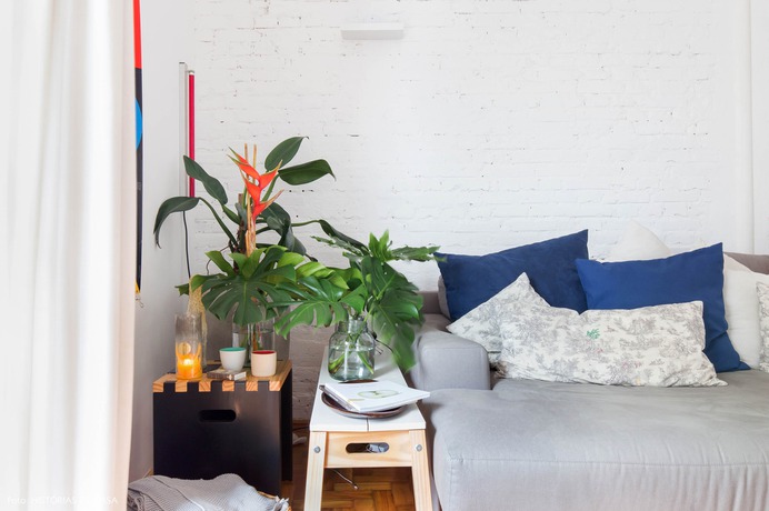 Room with white brick wall and many plants on the side of the sofa