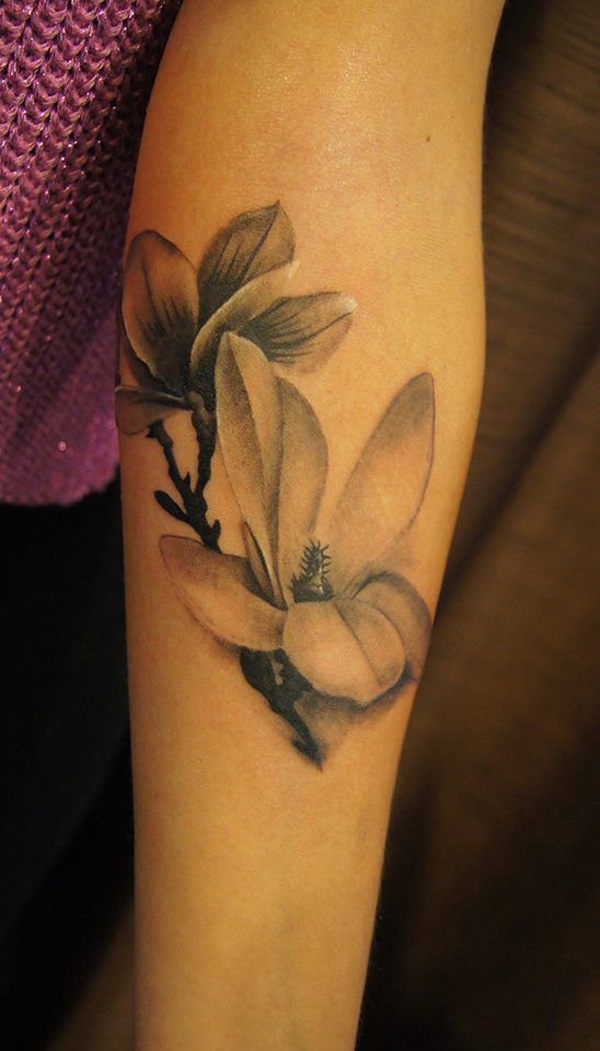 Black and white magnolia forearm sleeve tattoo in a realistic style.