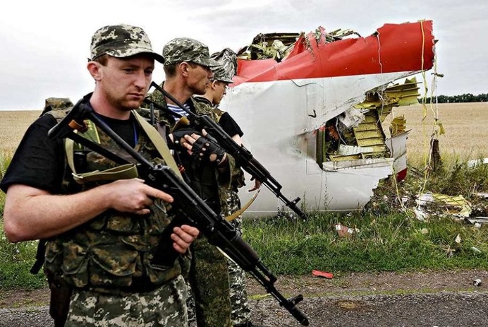Armed Russian-backed militants pass next to the wreckage of a MH17 flight which crashed during flight over Donetsk