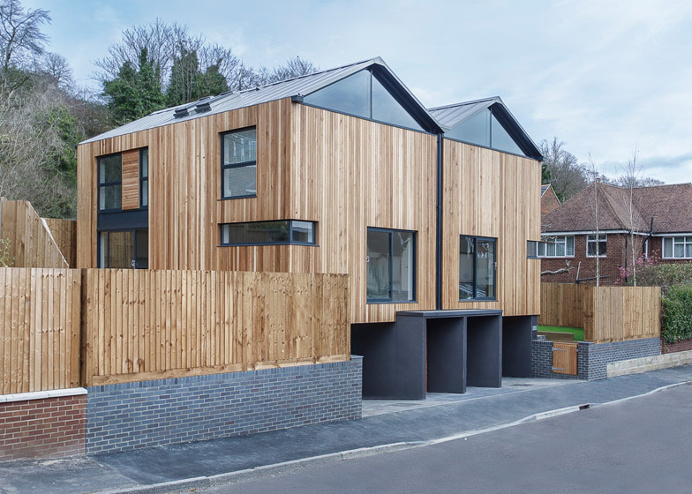 Twin wooden houses by Adam Knibb Architects are raised up above street level