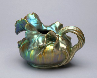 Squat bulbous gourd form with a large leaf-shaped spout and handle in the form of a gathered root or vine; green and gold iridescent luster finish.