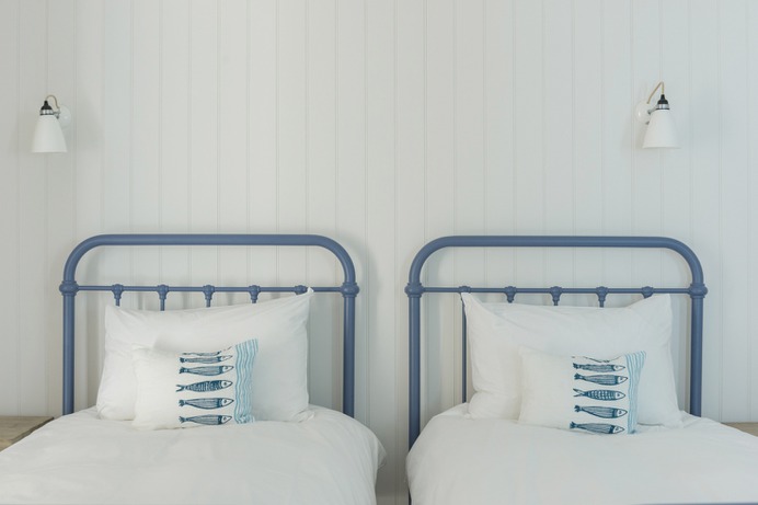 Pillows embroidered with fish imagery reference the sea right outside its windows. Photograph by David Curran, courtesy of Millard & Flo, from The Life Aquatic in Cornwall: A Waterfront House—and One-Time Dinghy Club—Reinvented. @marttan