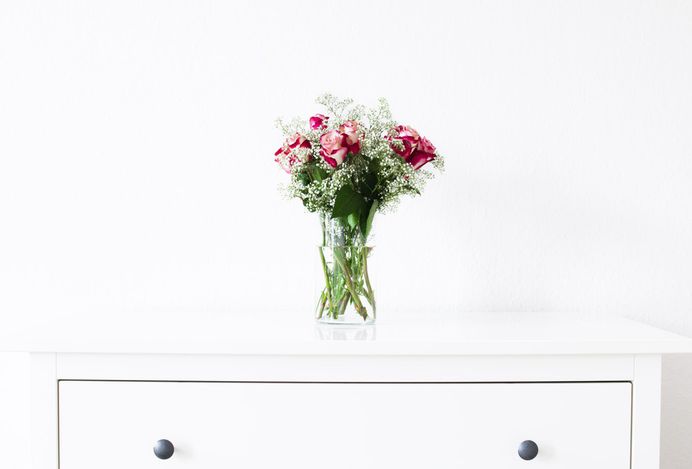 A bouquet of roses in a glass vase on a white cabinet